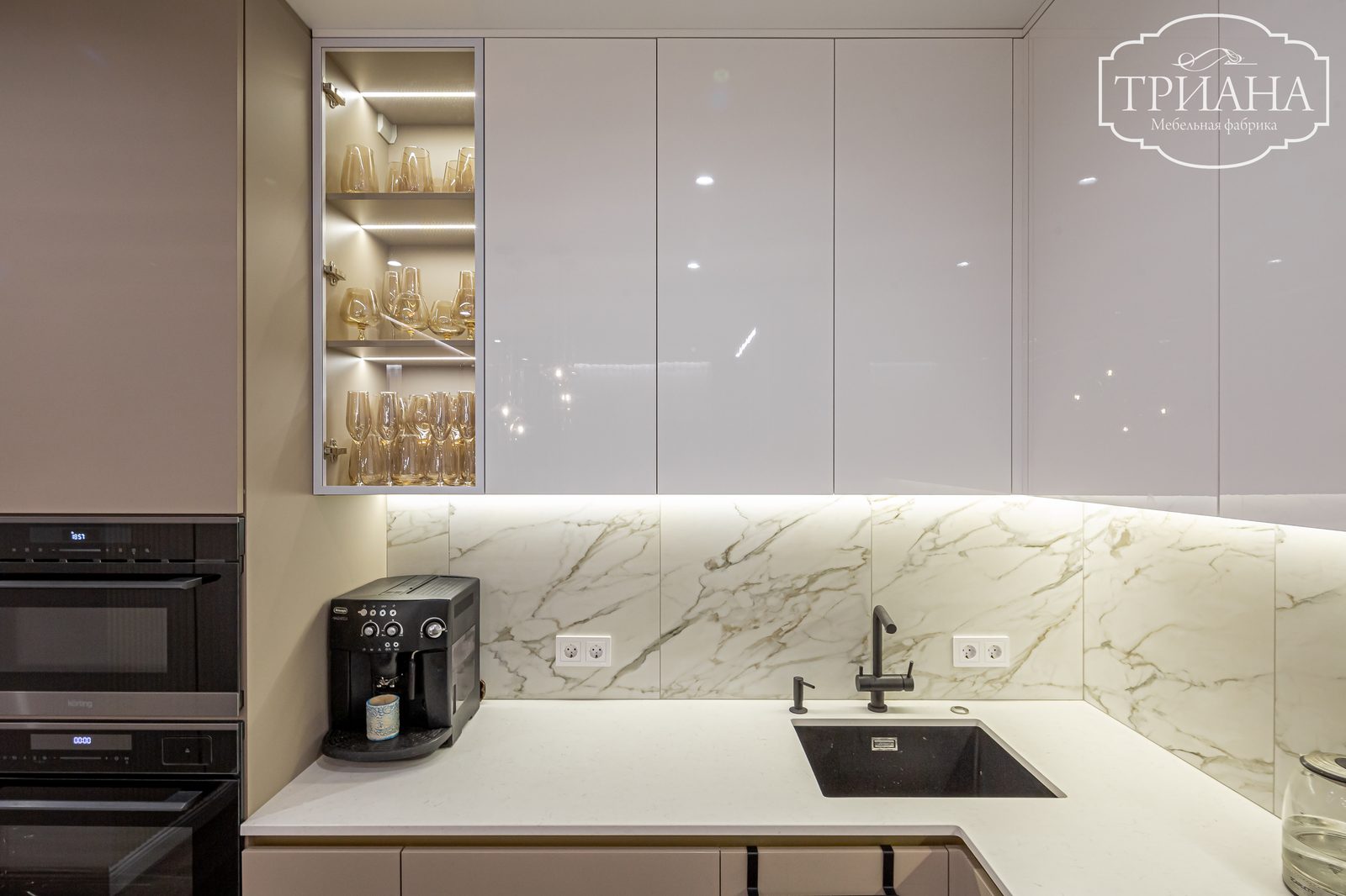 Витрина для бокалов с LED-подсветкой и глянцевые верхние шкафы кухни на фоне мраморного фартука